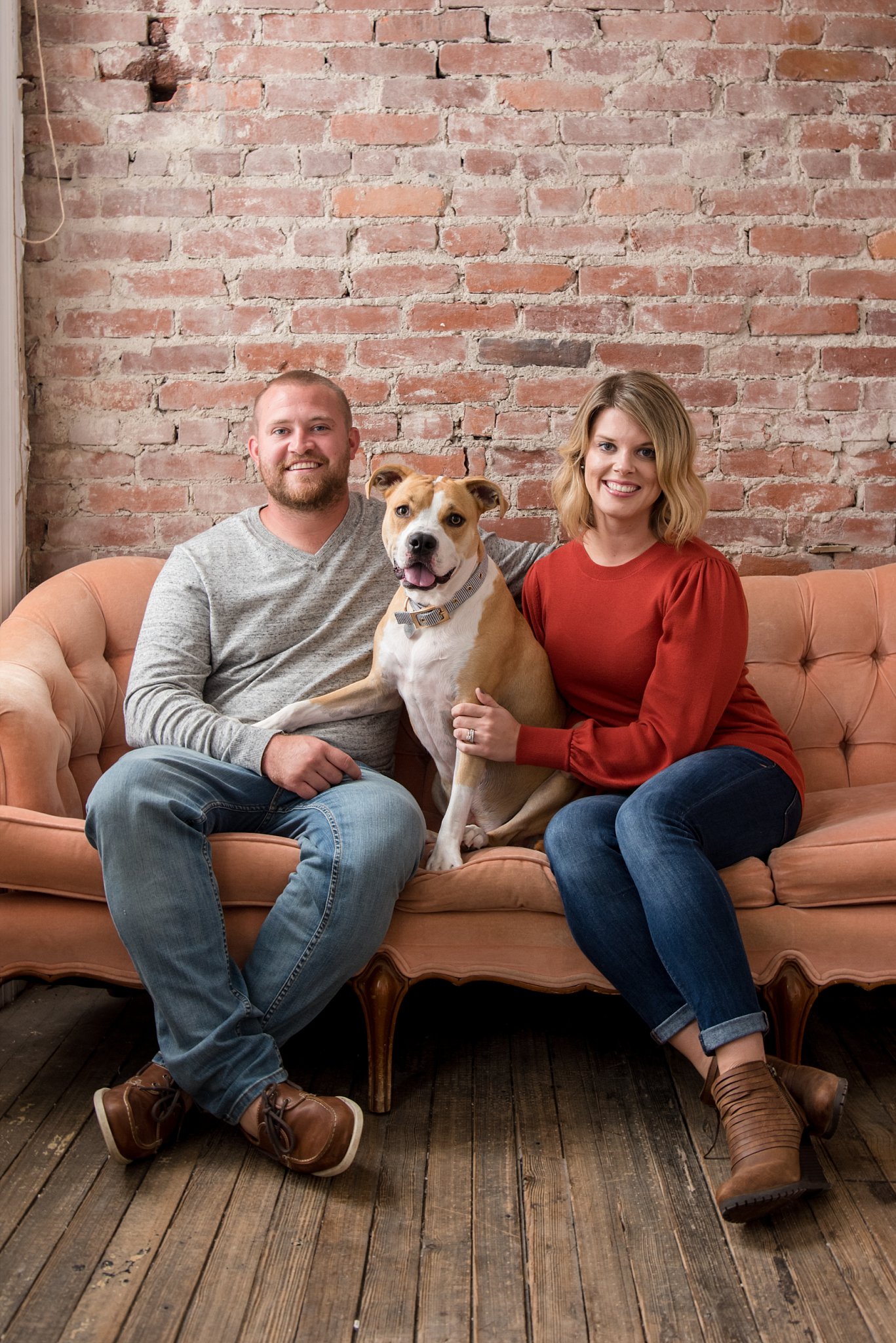 couple posing with pit bull on vintage pink couch at a Pittsburgh studio