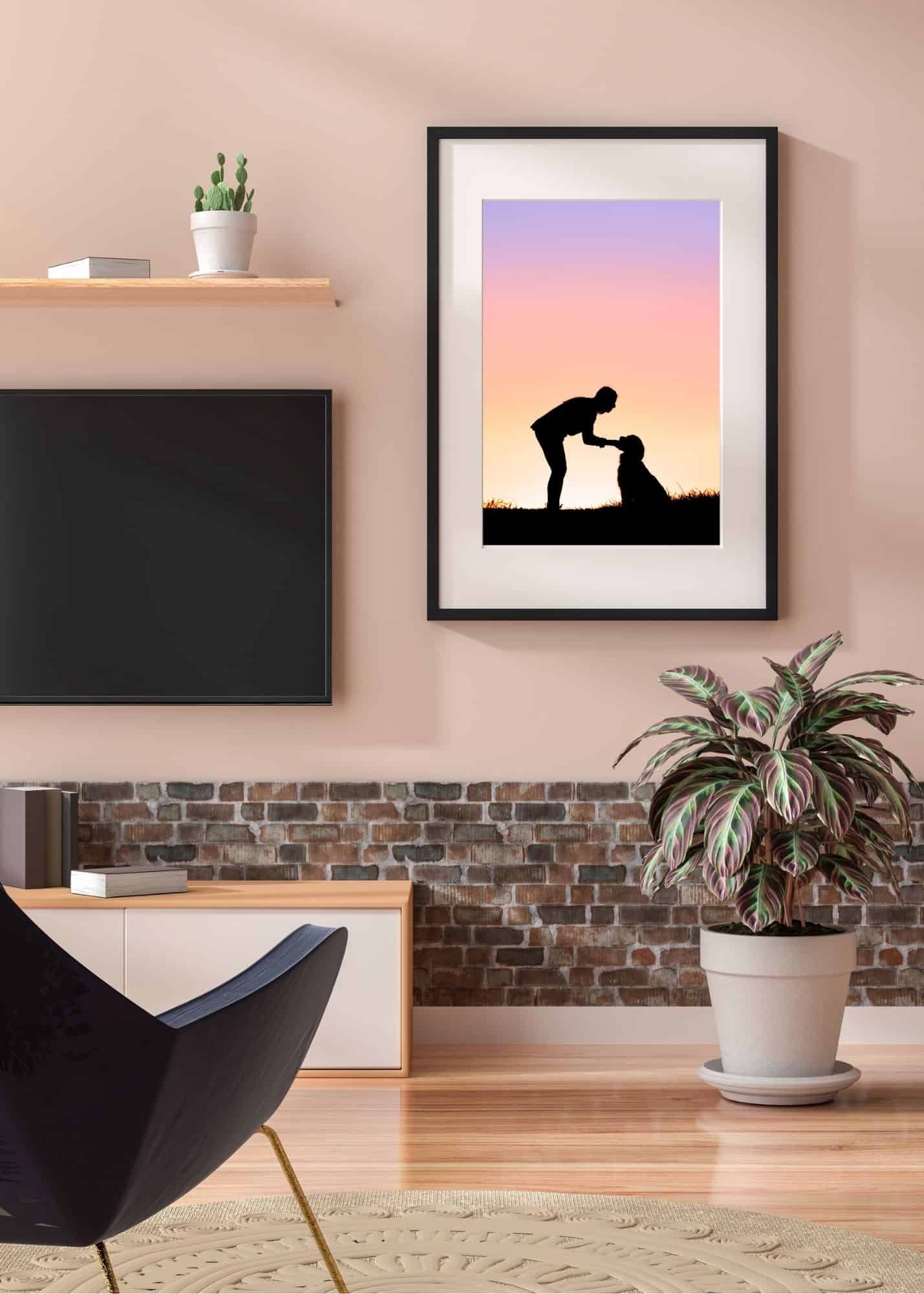 pale pink modern living room with a black framed and matted photo of a woman and her dog in silhouette against a sunset sky of pinks and purples